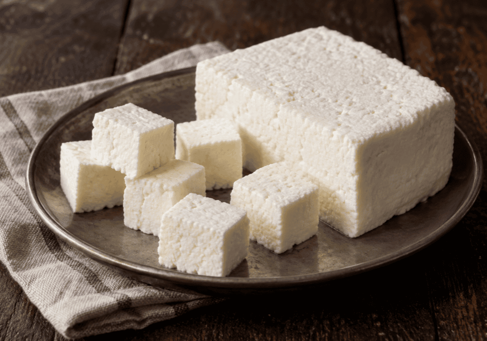 Fresh paneer cheese shown as a pressed block and cut into cubes.